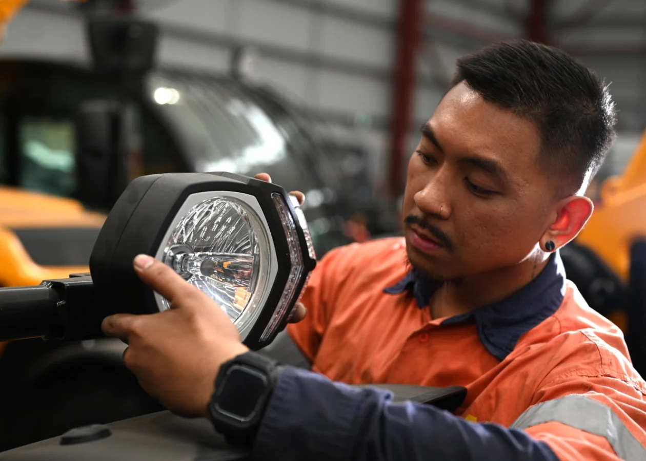 A mechanic inspecting a headlight on a dieci telehandler