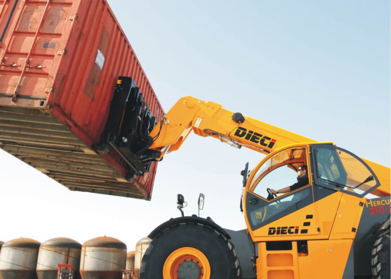 Dieci machine lifting a red shipping container at a warehouse site.