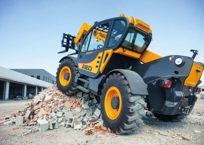 rear left view of a Dieci Samson 70.10 7T Telehandler with its boom raised and lifting forks out stopped on a pile of construction debris on a Sydney building project